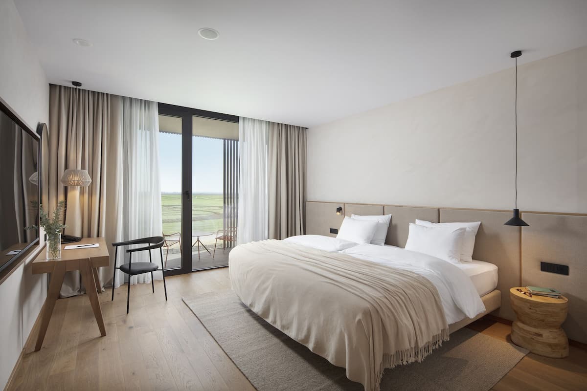 A modern hotel room with a large bed, a desk, and a chair.