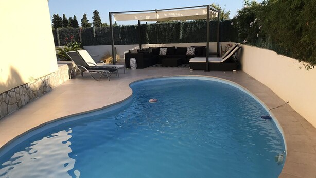 Ein Schwimmbecken mit Liegestühlen und einem überdachten Sitzbereich.