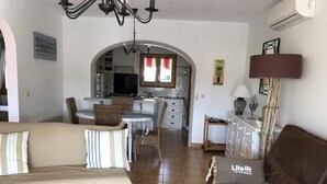 Ein Wohnzimmer mit einer Couch, einem braunen Sofa und einem Essbereich mit Tisch und Stühlen.