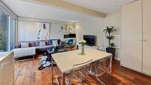 A modern living room with a sofa, TV, and a dining area with a table and chairs.