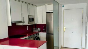 A compact kitchen with white cabinets, a red countertop, a stainless steel refrigerator, and a washing machine. - Ground Floor Apartment with Pool Access Near Beach in Miami Playa (Miami Playa)
