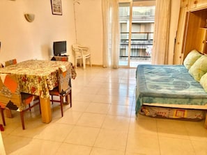 Cozy living space with a bed, dining area, and TV, offering a balcony view.