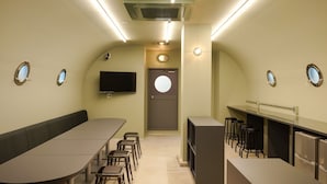 Una cocina moderna con una encimera larga, taburetes y un televisor montado en la pared.