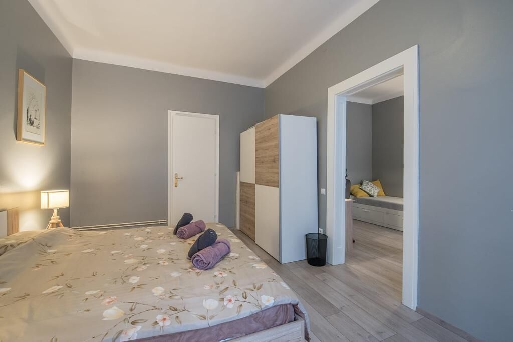Un dormitori amb un llit, un armari i un bany visible a través d'una porta oberta.