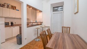 Una cocina compacta con armarios blancos, una encimera y un comedor con una mesa y sillas de madera.