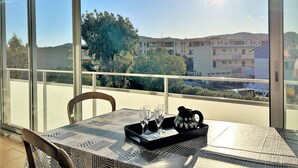 A balcony with a table set for two, a chair, and a view of buildings and trees. - Cozy 1BR Apt with Terrace, 150m from Beach, Parking Included - Bormes-les-Mimosas (Bormes-les-Mimosas)