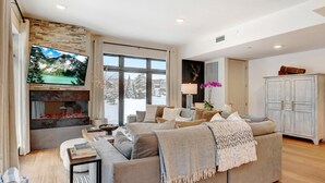 Un salon spacieux doté d’une grande fenêtre, d’une cheminée et d’un coin salon confortable.