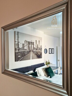 A bedroom with a large framed picture of a bridge, a bed with pillows, a small table, and a potted plant. - Business Stays| Monthly Discount |Central Location (Somerset)