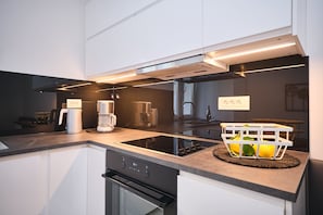 Una cocina moderna con estufa, horno y cafetera integrados.