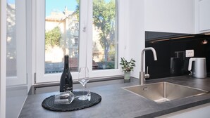 Cozinha moderna com uma janela ampla, uma pia de aço inoxidável e uma garrafa de vinho no balcão.