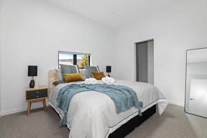 A bedroom with a bed, bedside tables, a window, and a door. - Inn Sophia - Two Homes, Spa Pools, Sleeps 10 (Rotorua)