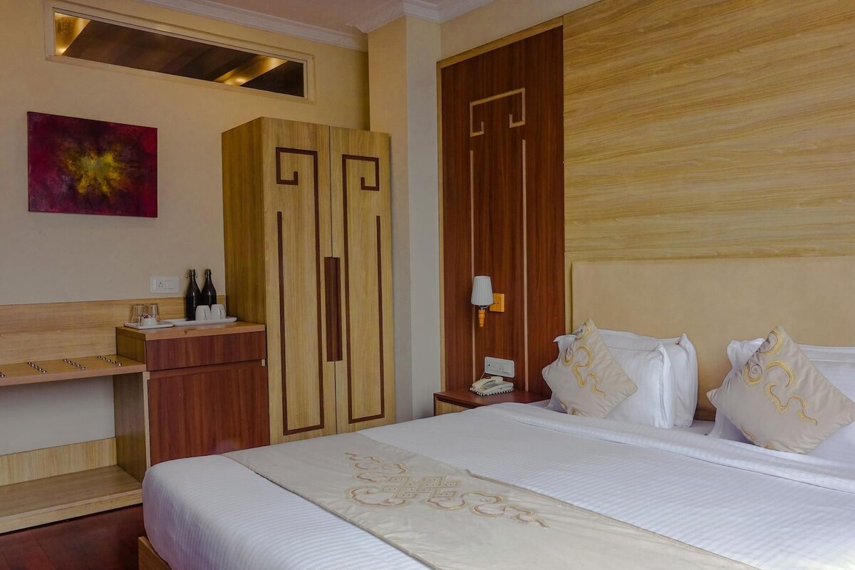 A hotel room with a bed, a desk, a wardrobe, and a nightstand.