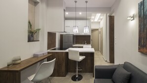 Eine moderne Küche mit einer zentralen Kochinsel, einem Essbereich mit einem weißen Stuhl und einem grauen Sofa.