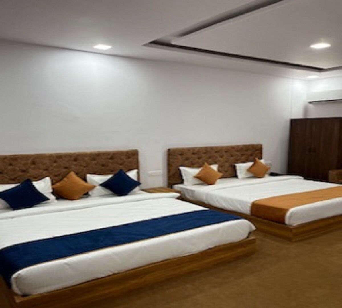 Habitación de hotel con dos camas, cada una con cabecero de madera y ropa de cama blanca.