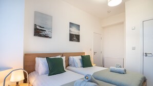 A hotel room with two beds, a nightstand with a lamp, and two wall-mounted paintings. - Isimi Luxurious 4 bed 4 en -suite House Cumbria (Barrow-in-Furness)