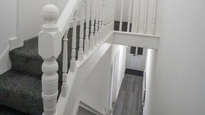 A staircase with white balusters and a dark carpeted landing. - Isimi Luxurious 4 bed 4 en -suite House Cumbria (Barrow-in-Furness)