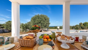 A breakfast setup with a view of a pool and trees. - 3670 Villa Perlaianca by Perle di Puglia (Carovigno)