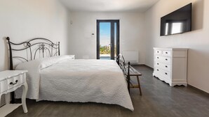 A bedroom with a bed, bedside table, dresser, and a TV on the wall. - 3670 Villa Perlaianca by Perle di Puglia (Carovigno)