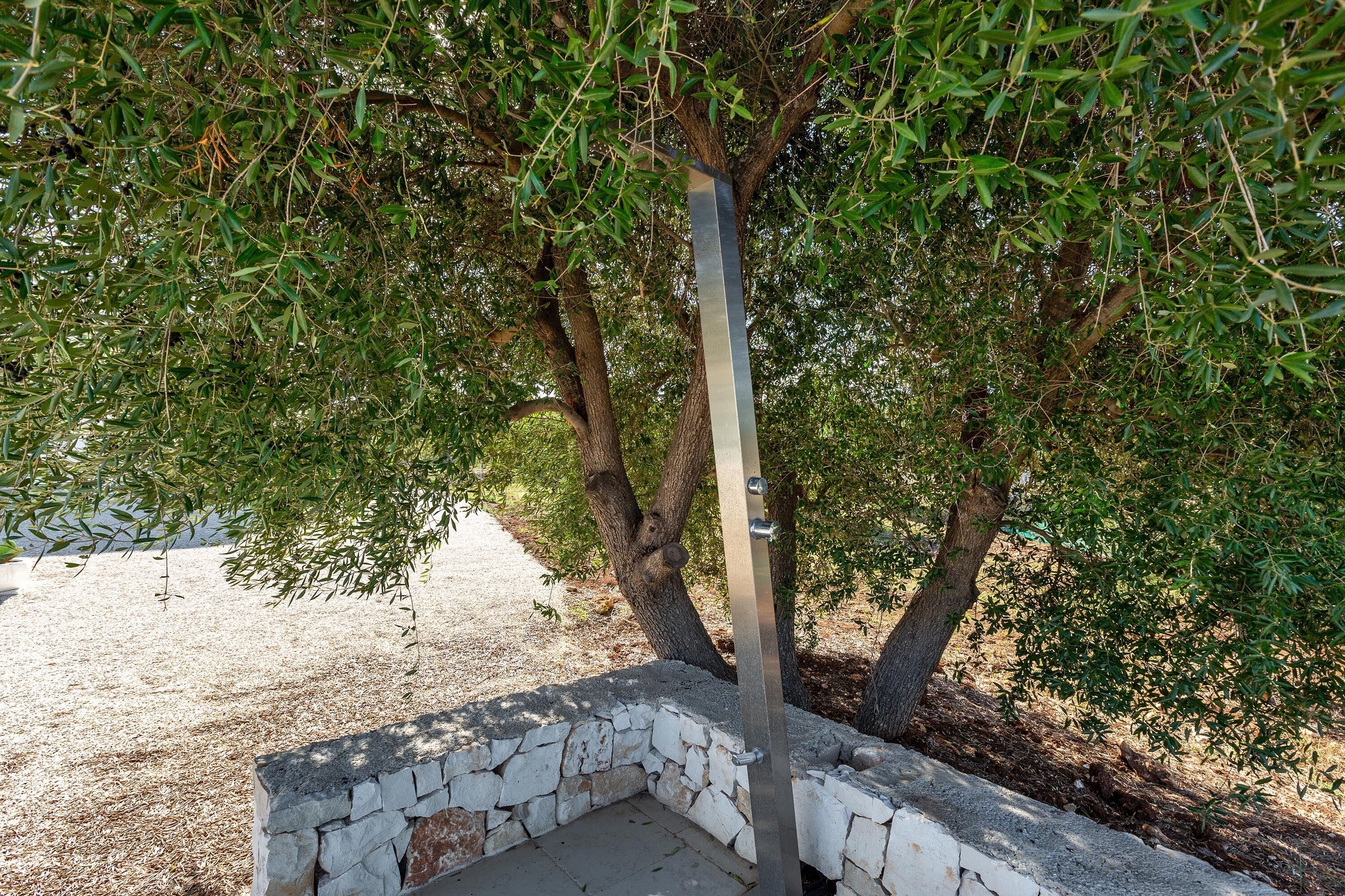 A stone bench under a tree with a metal post.