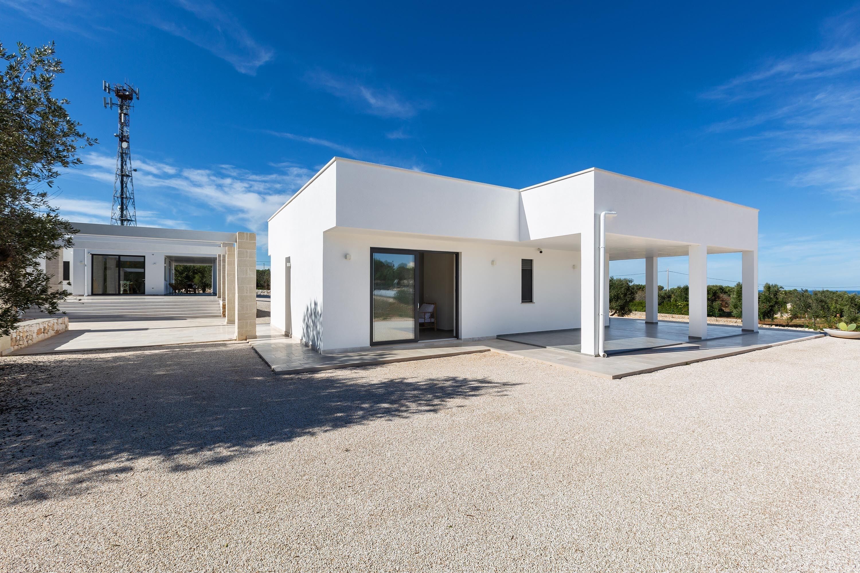 A modern, single-story building with a flat roof, large windows, and a covered outdoor area.