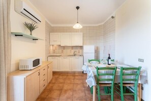 A compact kitchen with white cabinets, a microwave, a sink, and a dining area with a table and chairs.