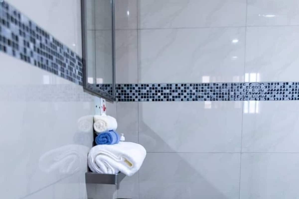 A bathroom with a white sink, a mirror, and a towel rack with folded towels.