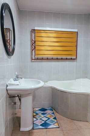A bathroom with a sink, a mirror, and a bathtub. - Ampric GuestHouse and Lounge  (Amasaman)