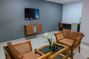 A living room with a sofa set, a glass coffee table, a TV mounted on the wall, and a small cabinet. - Ampric GuestHouse and Lounge  (Amasaman)