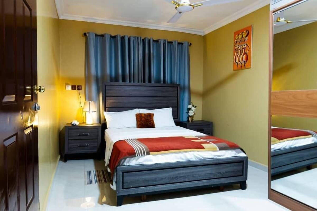 A bedroom with a bed, nightstands, a mirror, and a ceiling fan.