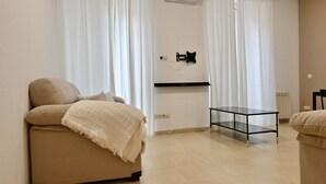 A room with a sofa, a glass table, and a mounted TV.