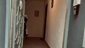 A hallway with a metal door, a wall-mounted intercom, and a tiled floor. - Lovely 1-bed Apartment in Koblenz (Koblenz)