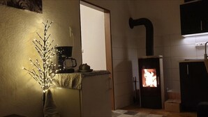 A cozy kitchen with a wood-burning stove, a coffee maker, and a decorative branch with lights. - Lovely 1-bed Apartment in Koblenz (Koblenz)
