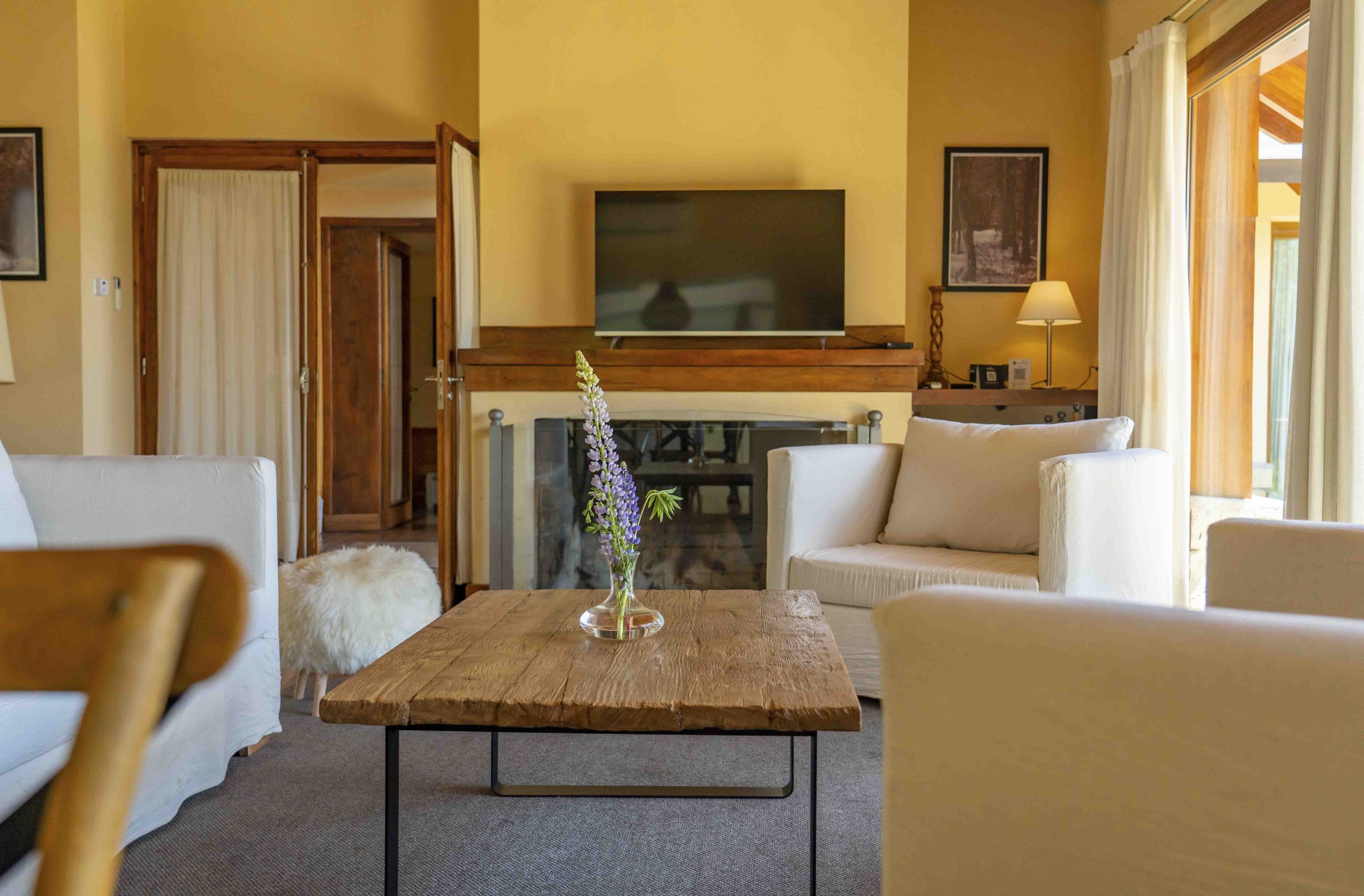 A living room with a fireplace, a flat-screen TV mounted above it, and a sofa set.