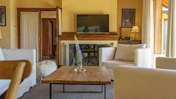 A living room with a fireplace, a flat-screen TV mounted above it, and a sofa set.