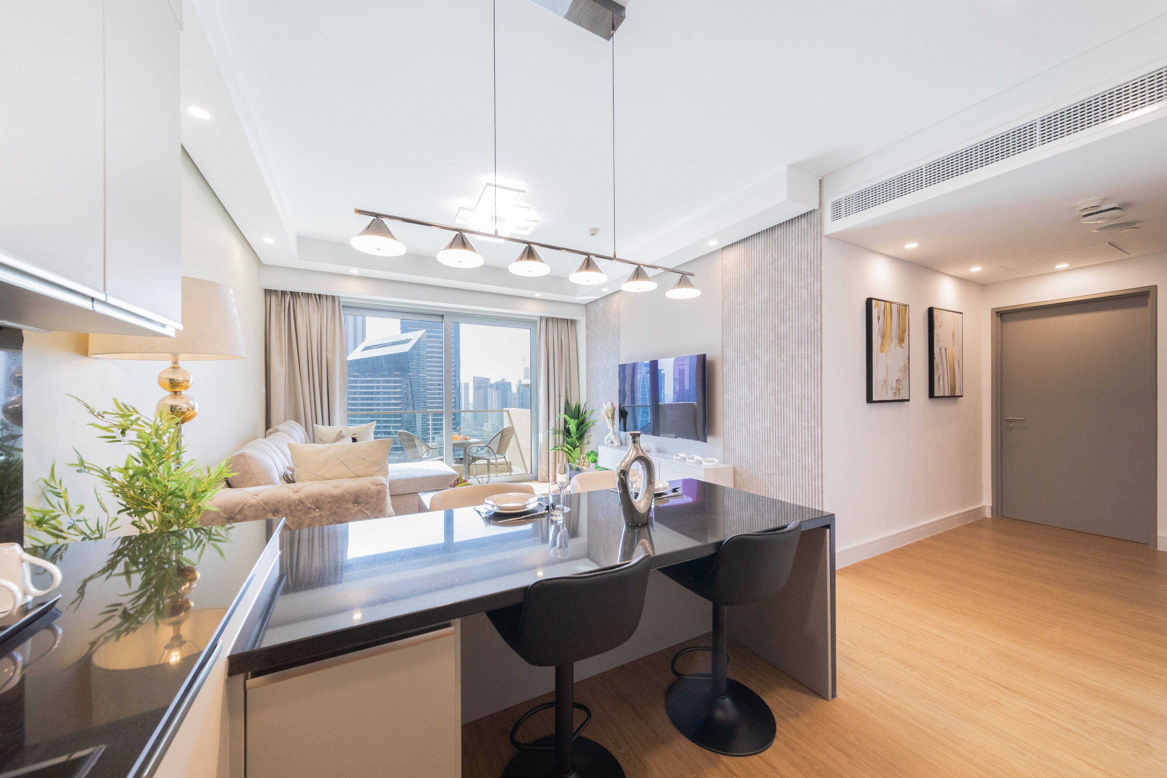 A modern kitchen with a central island, bar stools, and a dining area with a sofa and chairs.