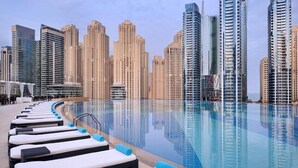 Un espace aménagé au bord de la piscine, avec des chaises longues et une vue sur le paysage urbain en arrière-plan.