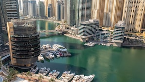 Un port de plaisance où sont amarrés de nombreux bateaux, entouré de grands immeubles et d’un bâtiment circulaire remarquable, doté de balcons.