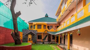 A courtyard with a green lawn, a stone wall, and a building with a green roof. - La Courtyard  (Vanur)