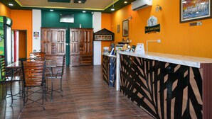 A restaurant with wooden chairs and a counter, a reception desk, and a sign reading "La Courtyard". - La Courtyard  (Vanur)
