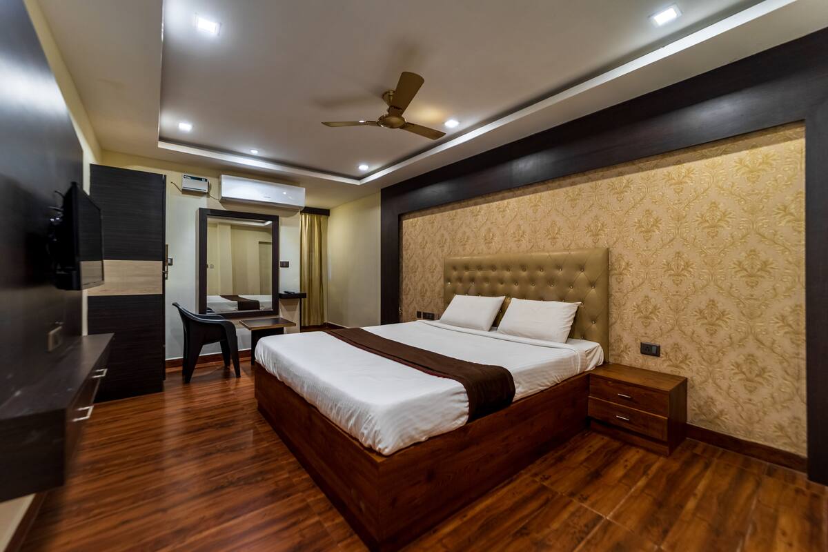 A modern bedroom with a large bed, a desk, and a ceiling fan.
