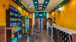 A bar with a variety of bottled drinks, wooden cabinets, and a counter with a patterned design. - La Courtyard  (Vanur)