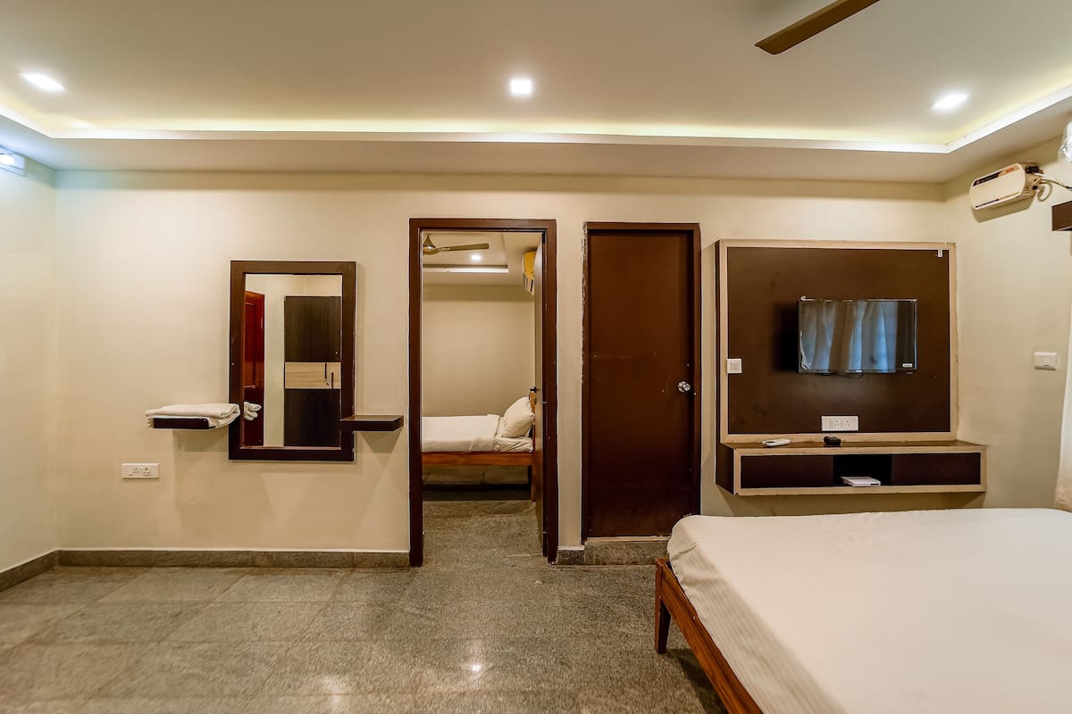 A hotel room with a bed, a TV, a wardrobe, and a mirror.