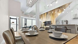Un espace de restauration moderne, avec une longue table en bois dressée pour un repas, entourée de chaises.