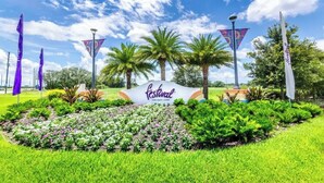 A sign for a festival with a grassy area and palm trees in the background.