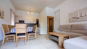 Un salon moderne avec un canapé, une table basse en bois et un coin repas comprenant des chaises et une table.