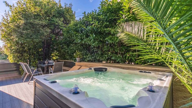 Un bain à remous entouré d’une végétation luxuriante et agrémenté de mobilier d’extérieur.