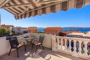 A balcony with a table and chairs, overlooking a coastal view with buildings and the sea. - Studio with fantastic balcony and sea view (Crikvenica)