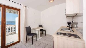 Une cuisine compacte avec un coin repas, une vue à travers une porte-fenêtre coulissante et un petit balcon.