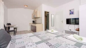 Une chambre avec un lit, un bureau, un coin cuisine et un téléviseur.