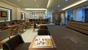 A modern hotel lobby with a reception desk, seating area, and a buffet table with food and drinks. - Fourseasons Hotel (Jeju City)